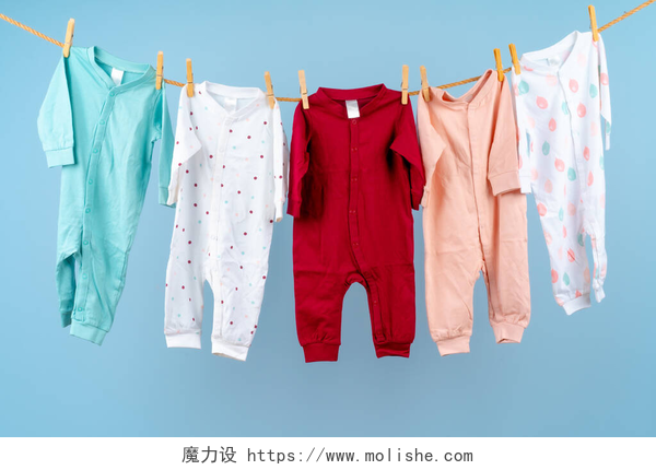 蓝色背景墙的五件婴儿衣服可爱的幼儿五颜六色的衣服挂在绳子上